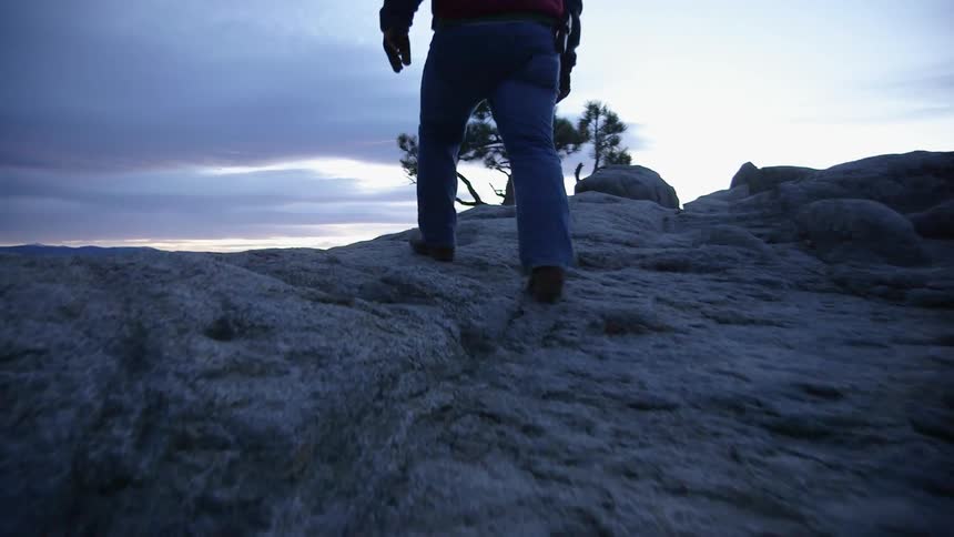 A man walks across a rocky hill