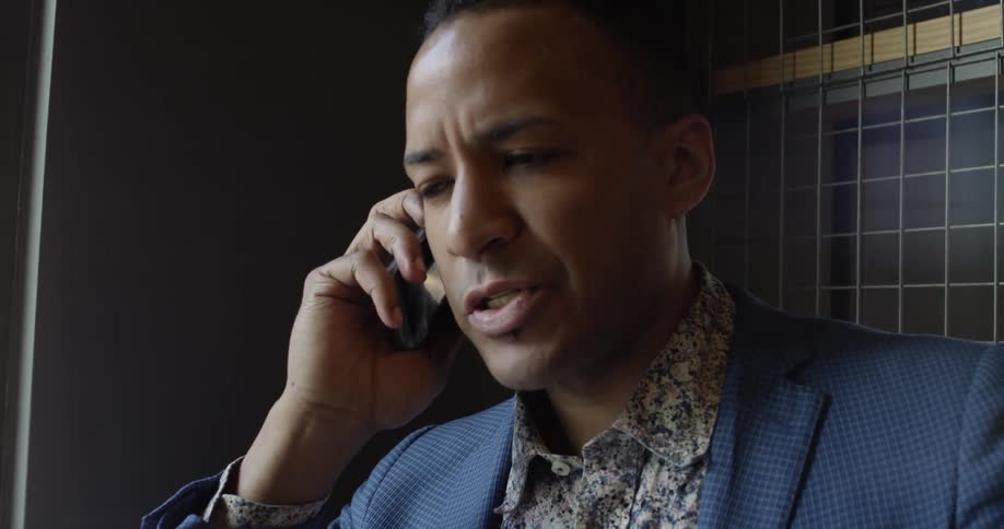 A man is talking on the phone by a window