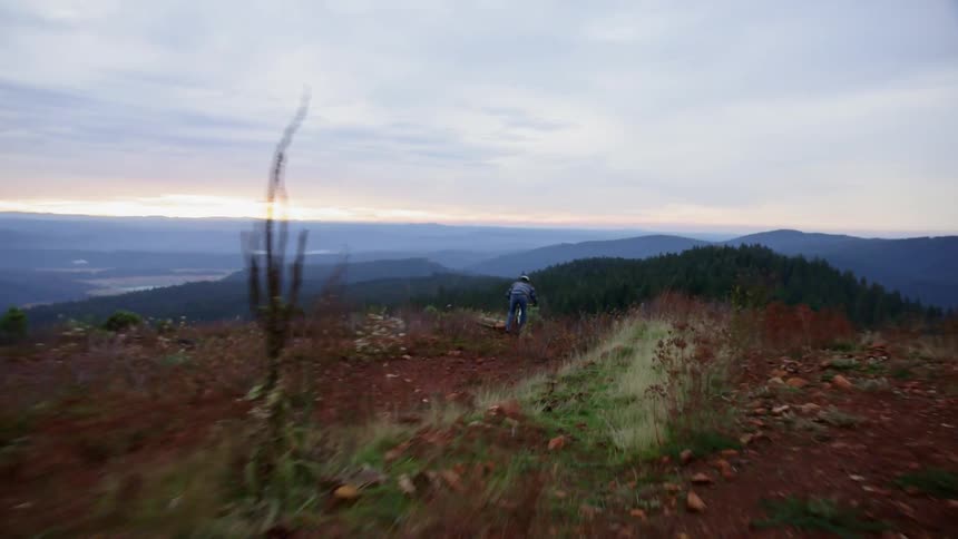 A person is mountain biking doing jumps on a hillside