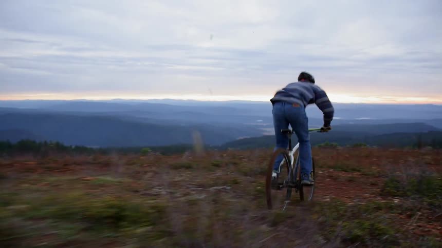 A man does jumps with his mountain bike on a rough field