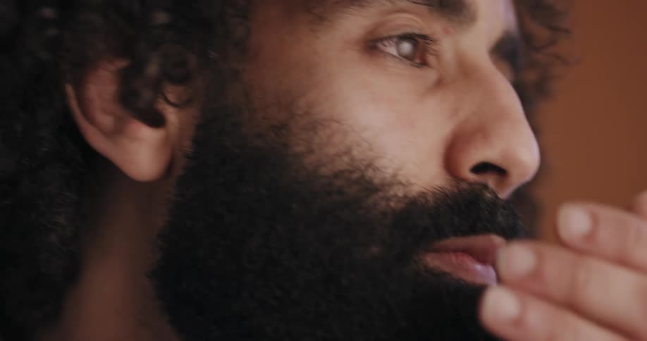 Man strokes his fully dark beard