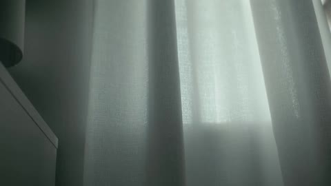 A person closes the drapes on a window indoors