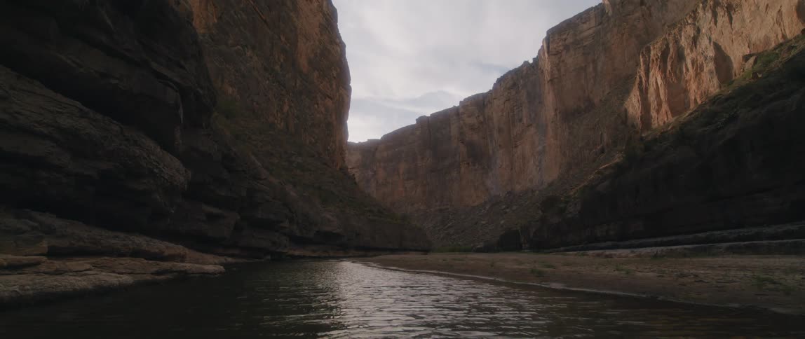 River flowing under the shadow of a mountain range in the desert at morning
