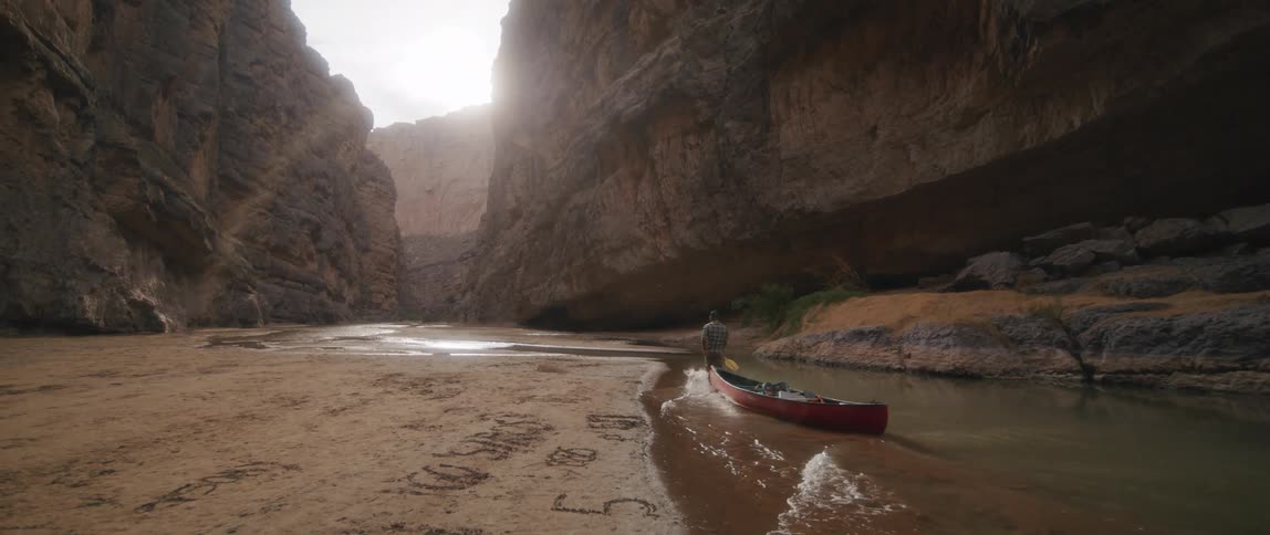 A man dragging a boat in a canyon