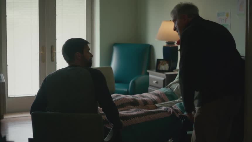 Man enters a hospital room greeting the family of a patient laying in bed