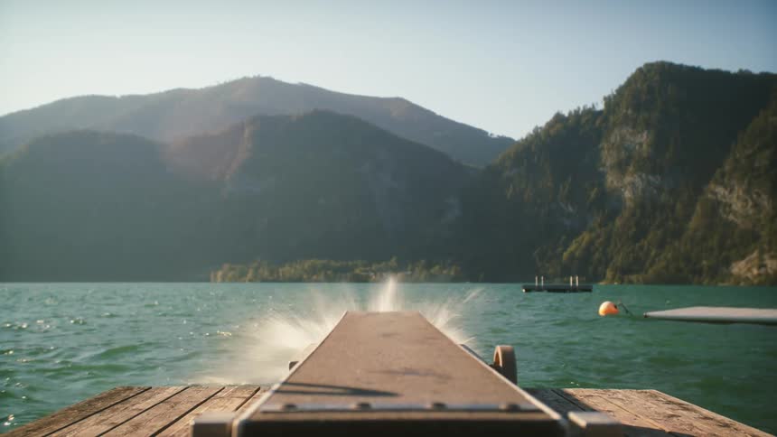 A man runs onto a diving board and jumps into the lake