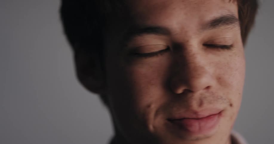 Teenage boy looks around solemnly then grins