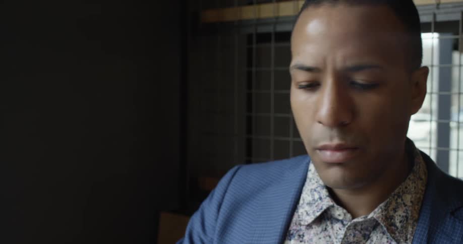 A man in a blue jacket works on his laptop
