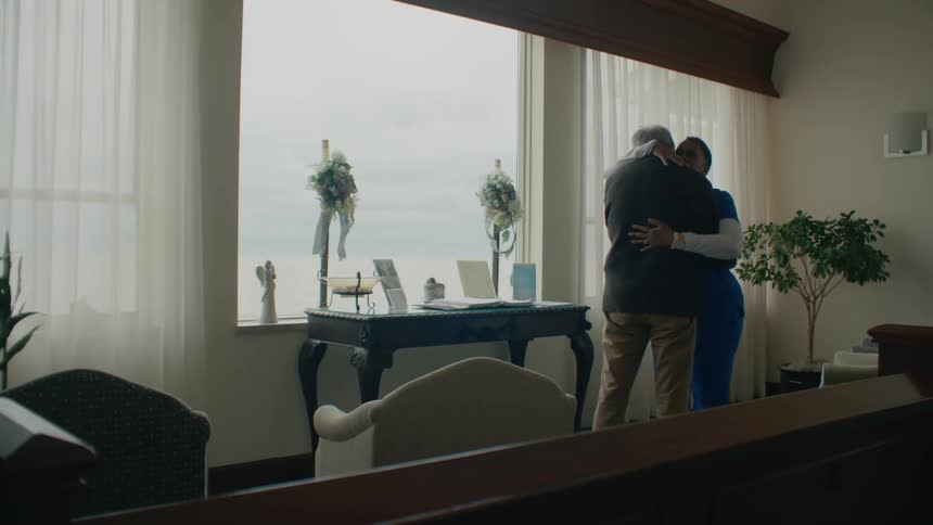Nurse hugs a senior citizen in the living room of a house
