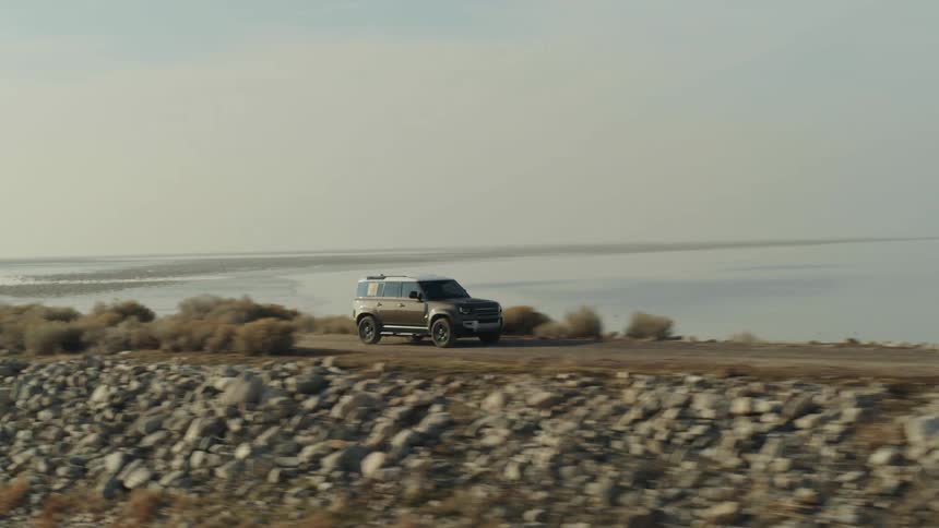A vehicle driving on the rocky coastal along a body of water