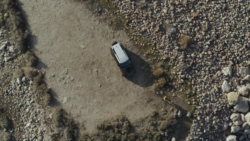 Aerial of person walking out of vehicle parked on dirt road