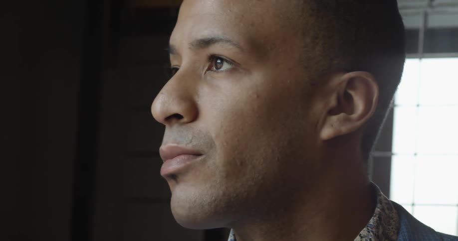 A man is looking around blinking by a window