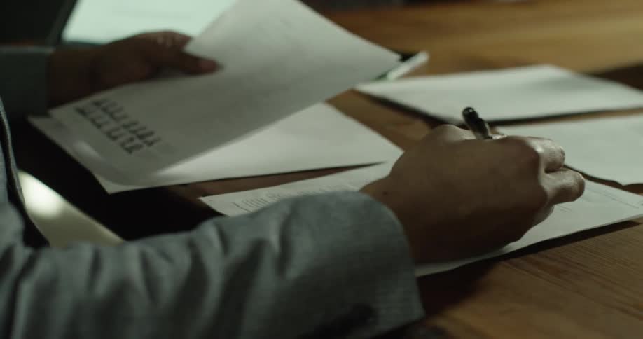 A person takes notes while reading papers