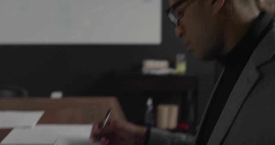 A man is typing and then circling something on paper