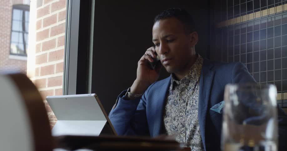 A man talks on the phone while looking at a computer