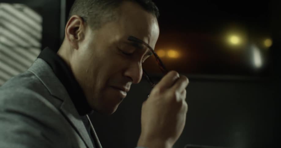 A man sits at a desk with paperwork and a tablet
