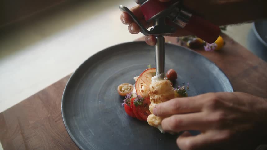 Person fills pastry sitting on plate on chopping board