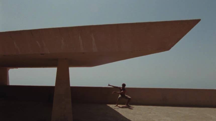 A man dances on a large balcony on a sunny day