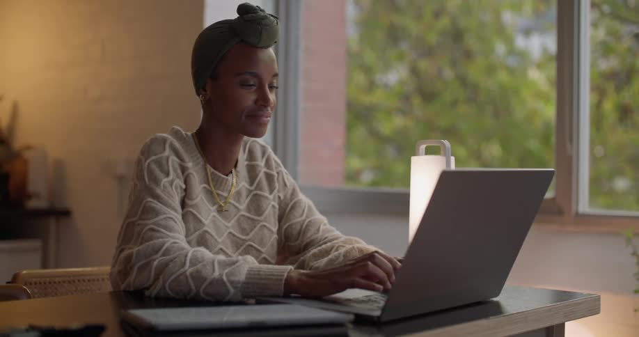 A woman smiles as she types on her laptop
