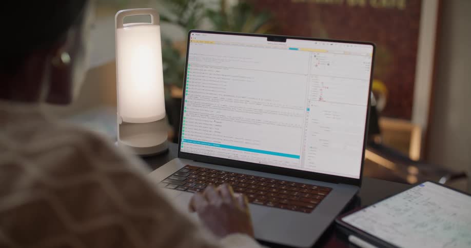 A woman is sitting at a desk working on a laptop computer