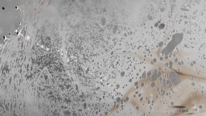 Dark liquid ink forming a film over a translucent surface and breaking away