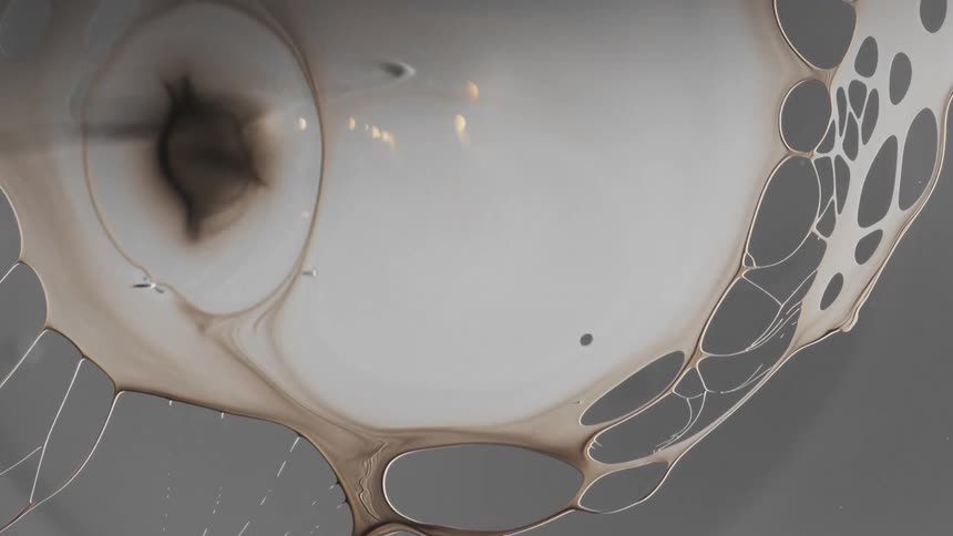 Dark liquid ink forming a film over a translucent surface and breaking