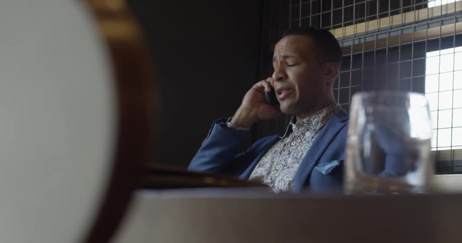 A man is sitting talking on a phone