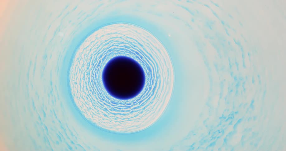 Waves of a blue and white substance move outward from a black hole