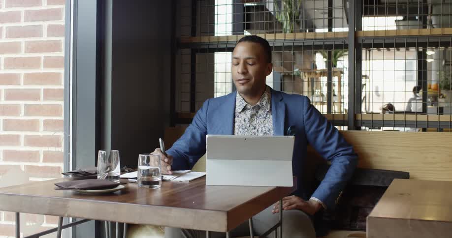 A man smiles as he looks away from his tablet briefly
