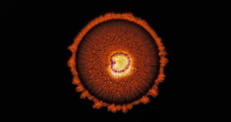 A sun like object grows orange rings and explodes in the darkness