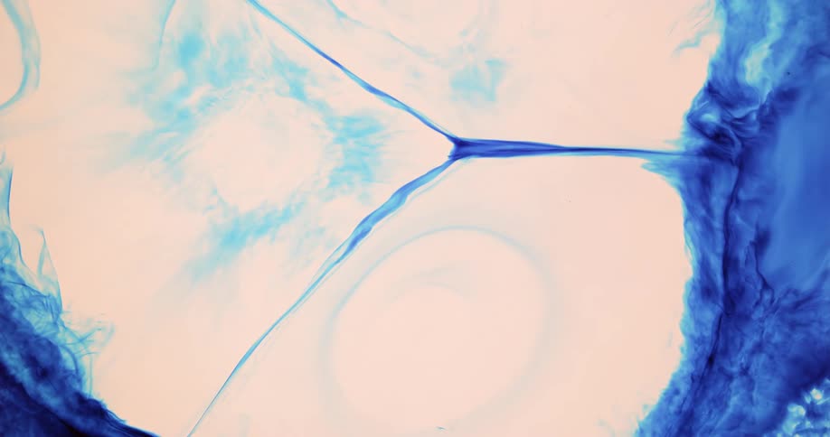 Droplets of bright white ink fall over and disperses a film of deep electric blue ink