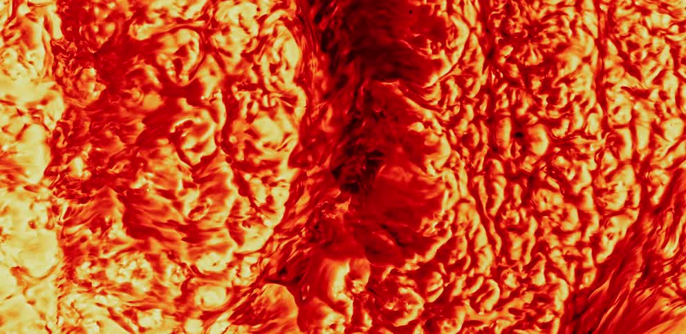 Textured mass brightly colored in reds and yellows flows as it expands