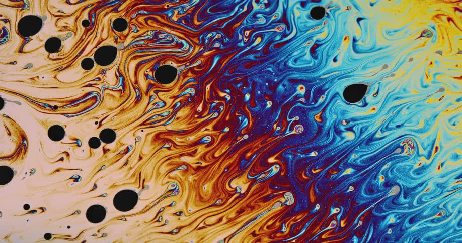 Liquid colors are moving and blending together as black round shapes move over the top