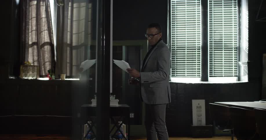 A man is writing on a board while holding papers