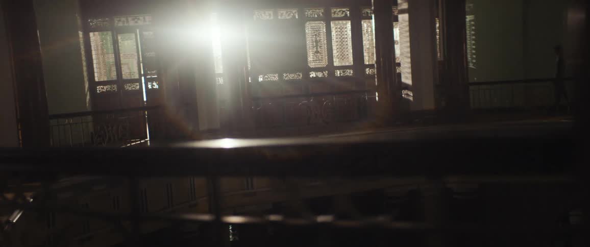 A man walks through a dark building with wooden floors and walls