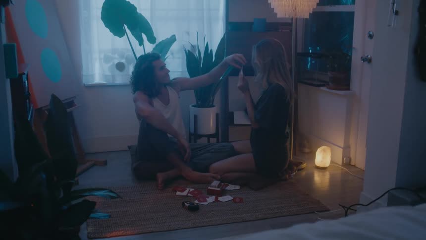 A man and woman are sitting on the floor of a home and playing with money