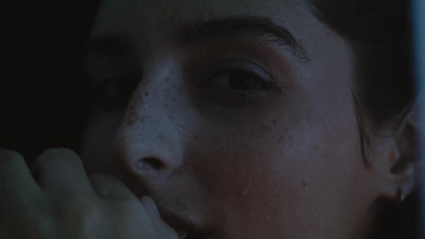 A woman is moving her hand on her face in the dark