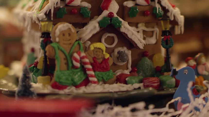 A model train moves past a gingerbread house