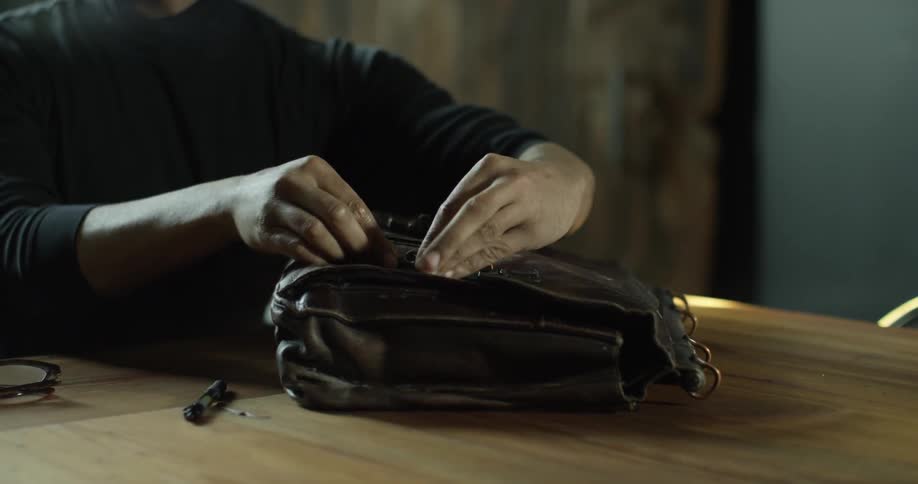 A man buckles his bag on the table