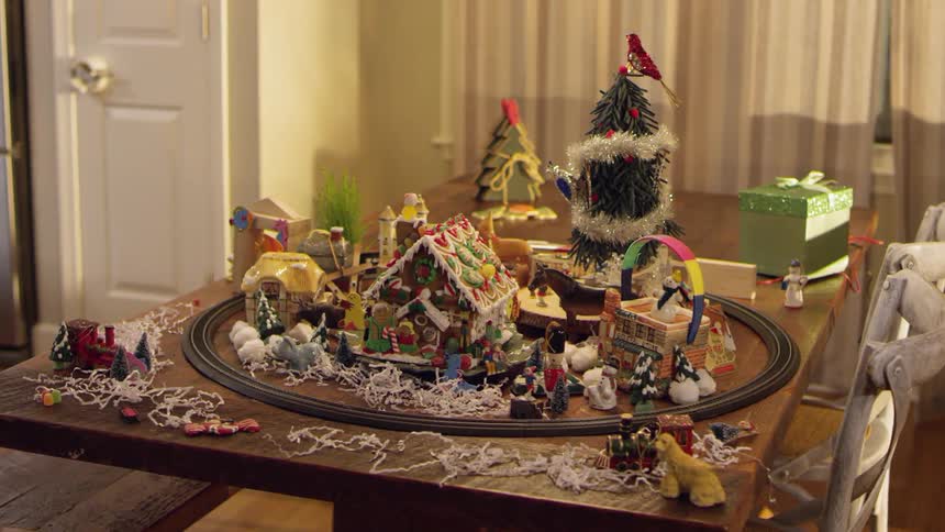 A toy train rides around some christmas decorations