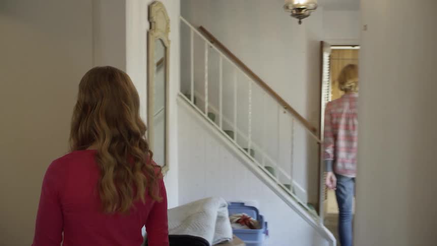 A woman turns on a record player and touches items in her home