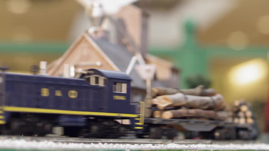 A toy train moves along its track while carrying a load of logs