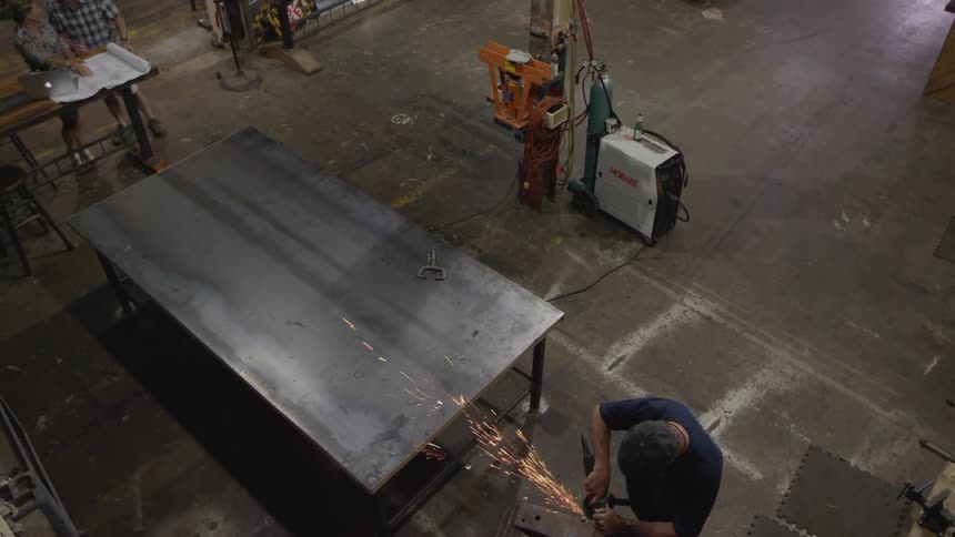 A man saws some metal in a workshop