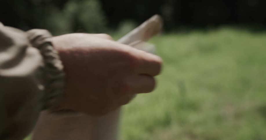 A person is standing outdoors and putting on gloves
