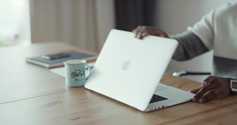 Man typing on laptop checks his watch then gets up and leaves