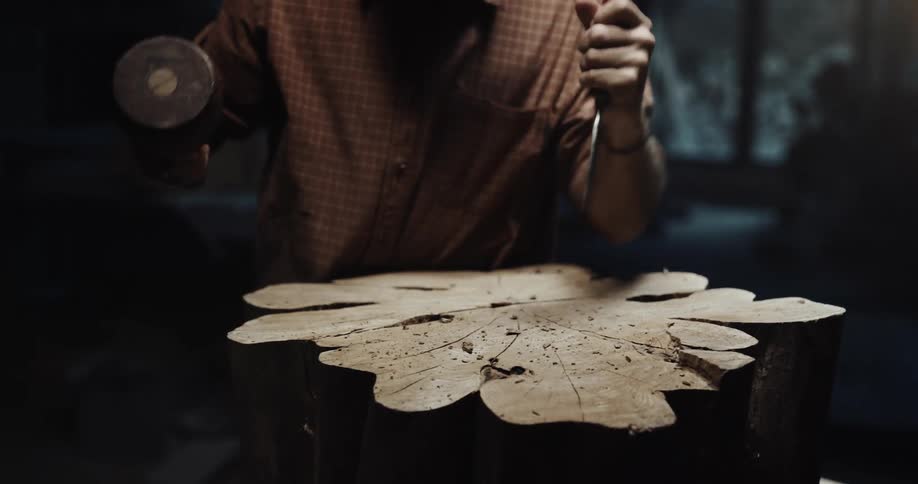 A view of a person chiseling a piece of wood