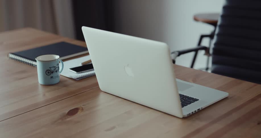 A laptop is set on a table next to a cup