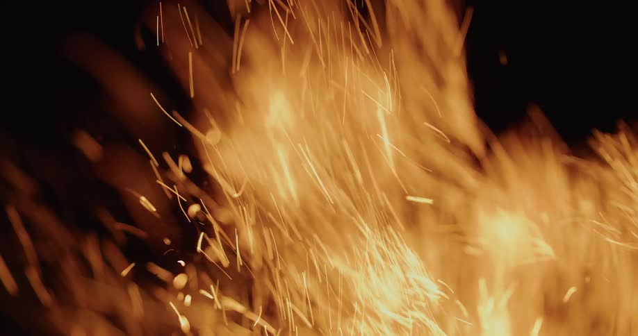 Flames and embers wave in the breeze as the wood of a campfire burns