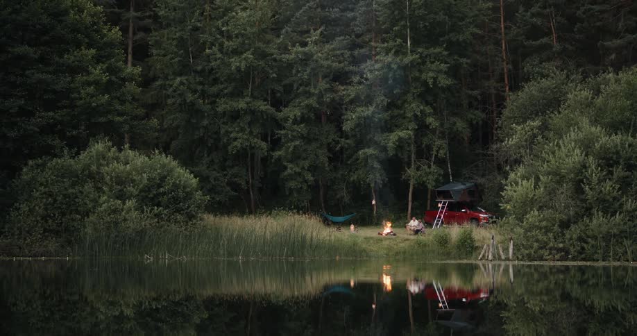 Camping near a lake in the wilderness relaxing by a bonfire