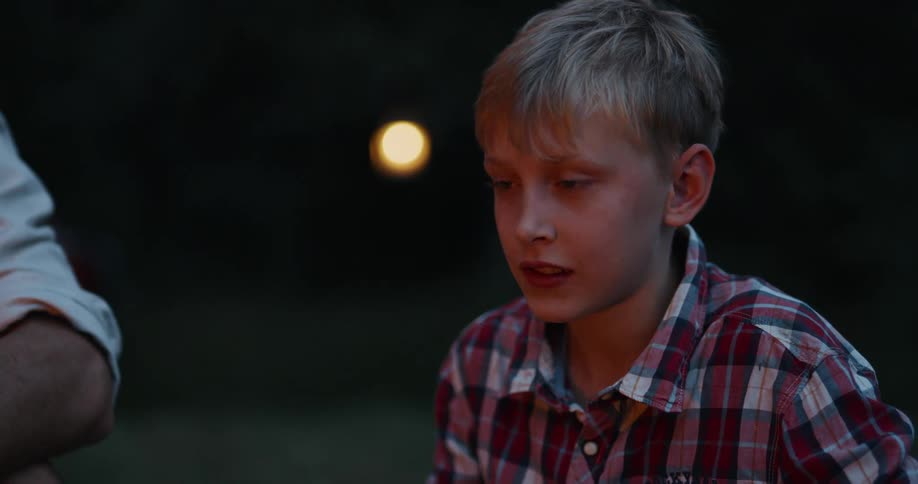 Father and son sitting around a campfire talking and laughing together